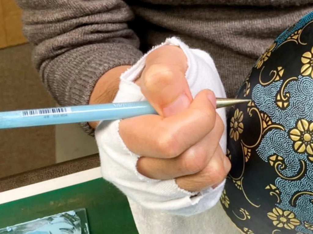The itchin tool, shaped like a pen, is used for the meticulous placement of dots in the aochibu technique.