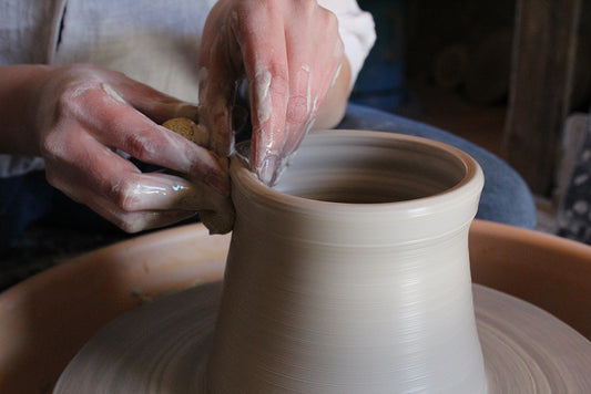 Craftsman shaping a wheel on a potter's wheel